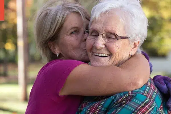 Adult daughter kissing senior mother on the cheek