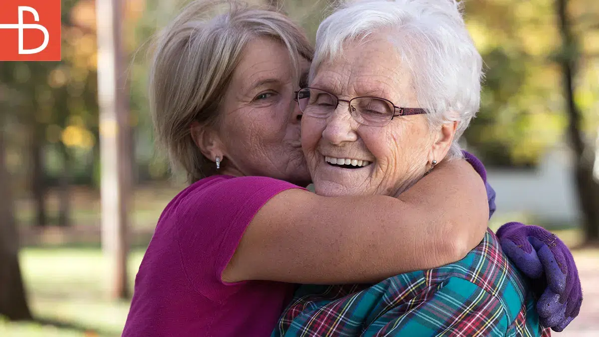Adult daughter kissing senior mother on the cheek